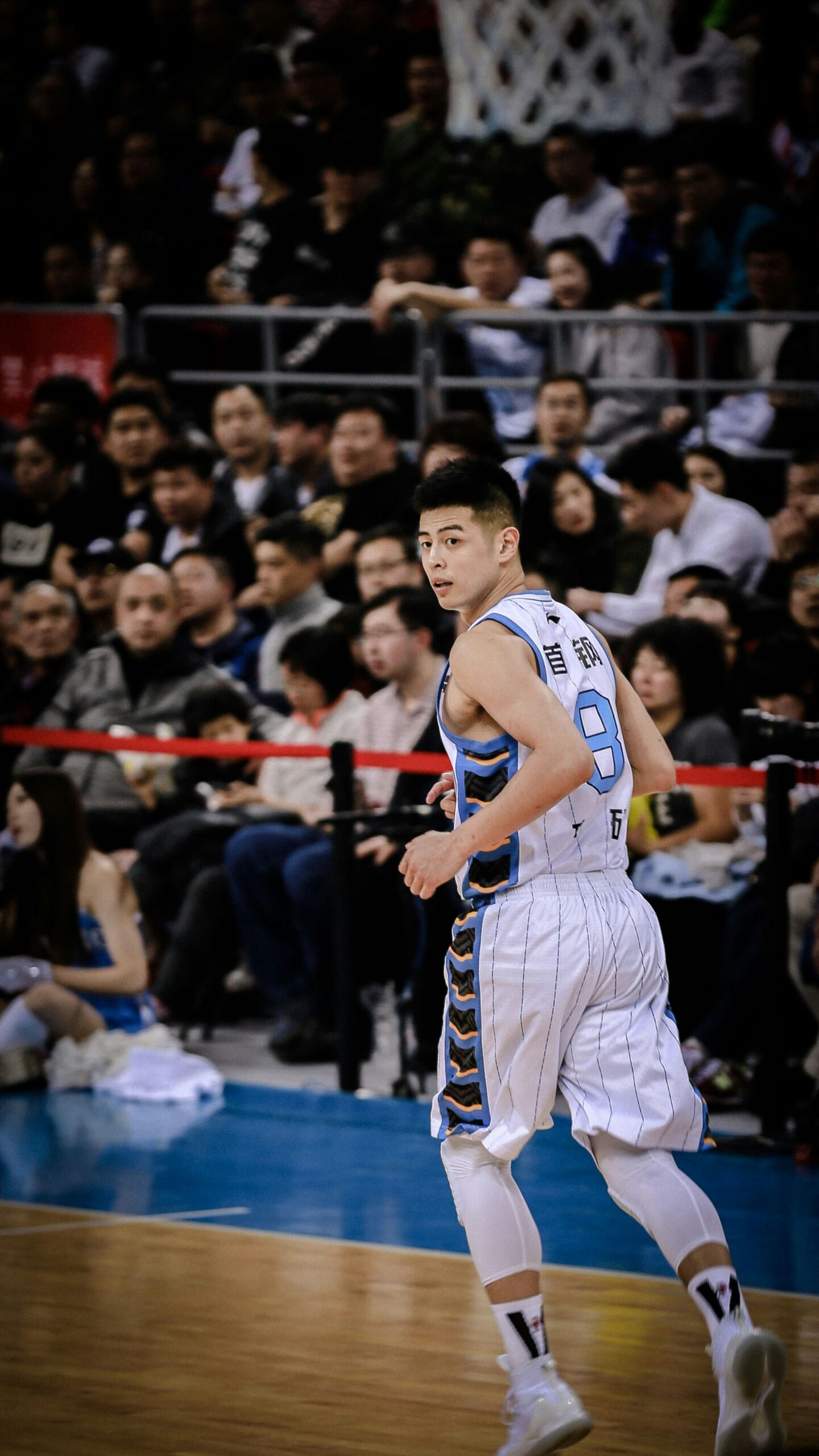 man wearing white and blue basketball jersey standing inside basketball field